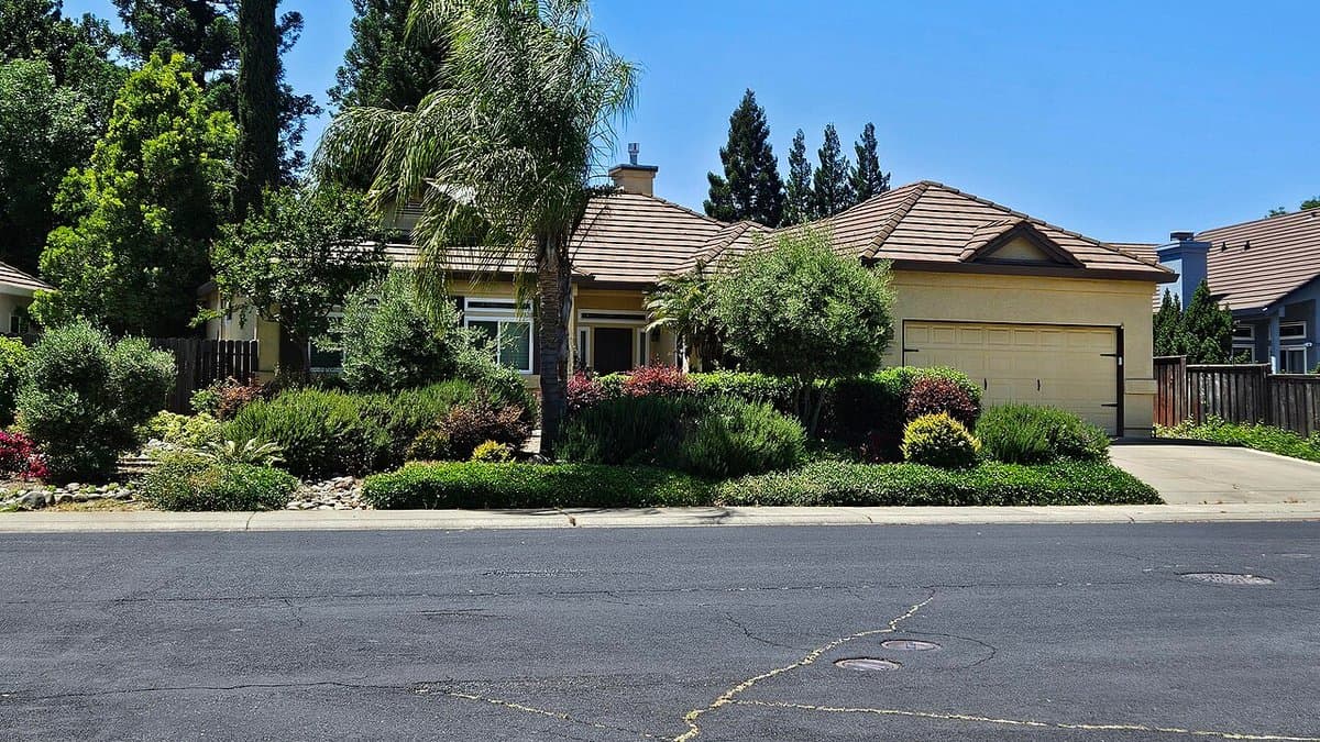 A single-story house in Roseville, California with a dense, mounding border of drought-tolerant shrubs along the front walkway instead of a lawn
