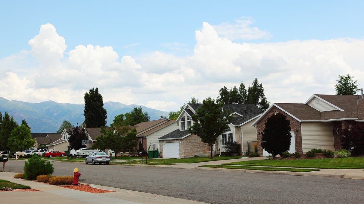 A suburban subdivision street with houses set back behind mowed lawns and a fire hydrant on the curb