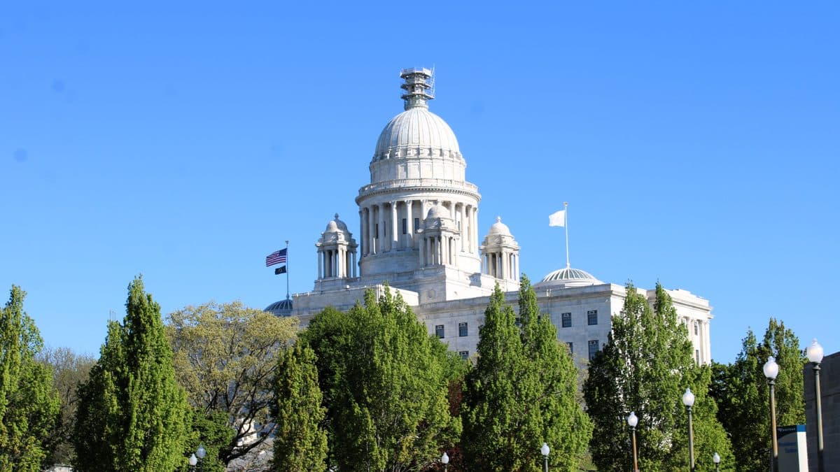 The white marble dome of the Rhode Island State House above a row of trees