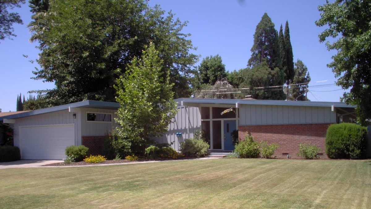 A single-story ranch house behind a wide mowed lawn